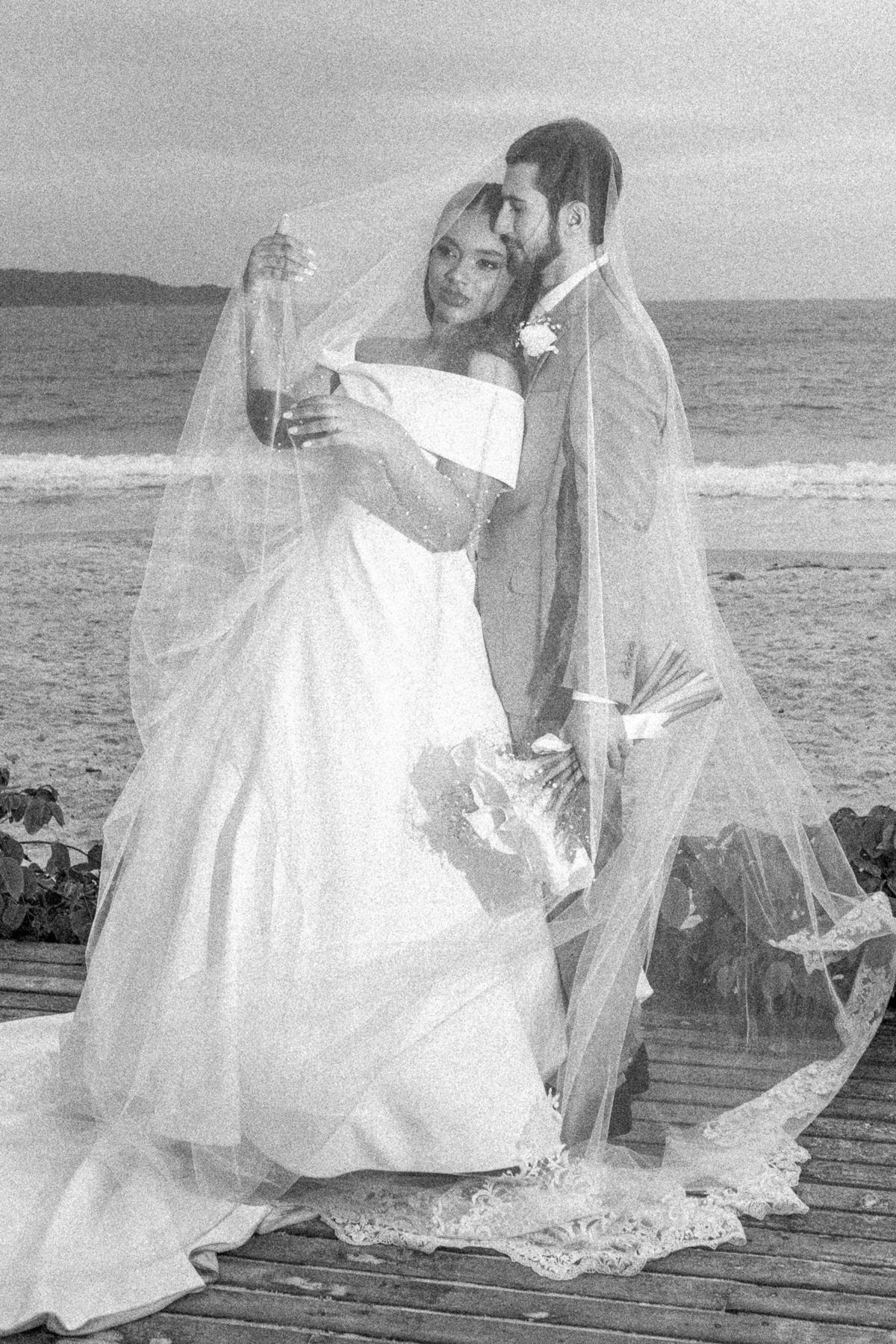 Casal em retrato artístico com véu diante do oceano