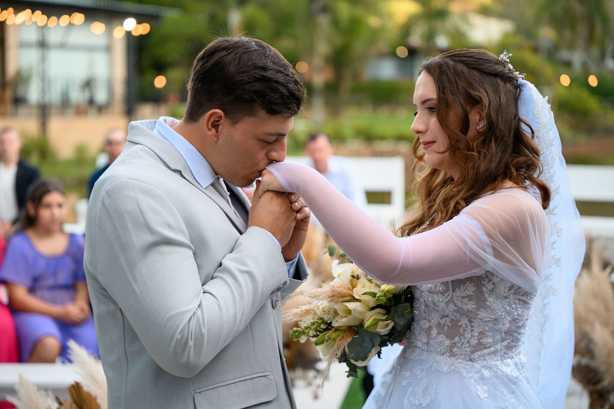Noivo beijando a mão da noiva durante a cerimônia