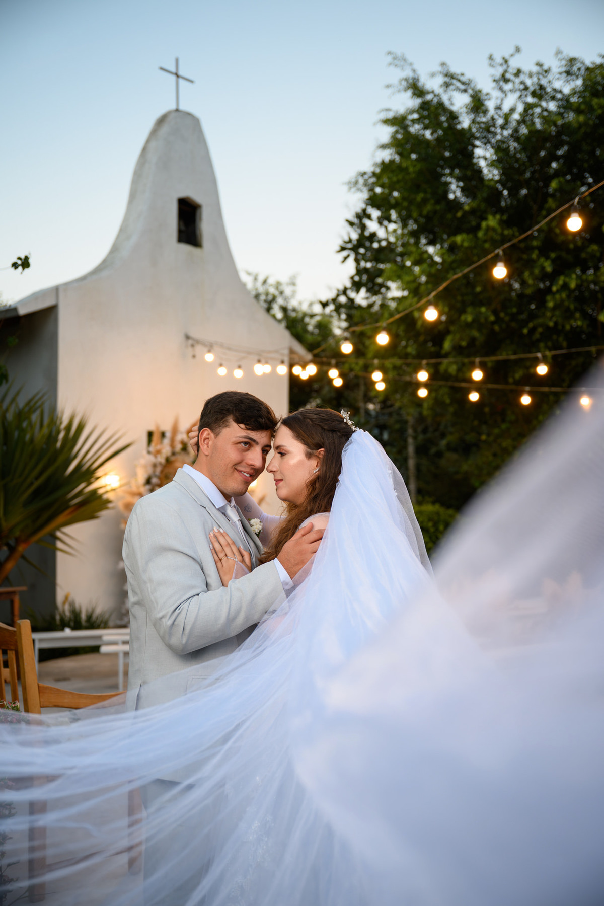 Casal se beijando com o véu em movimento no primeiro plano