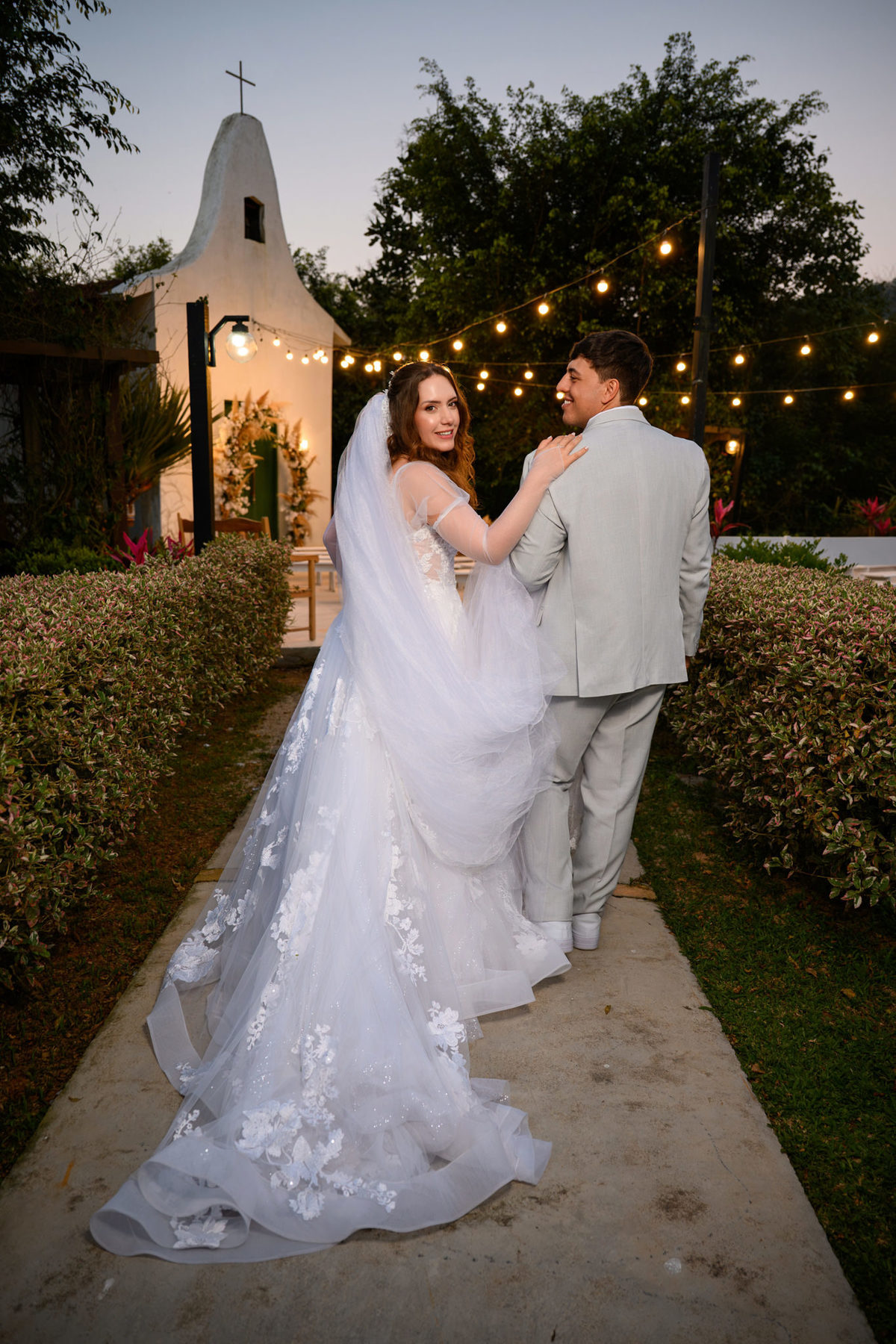 Casal caminhando de costas com o vestido e véu em destaque