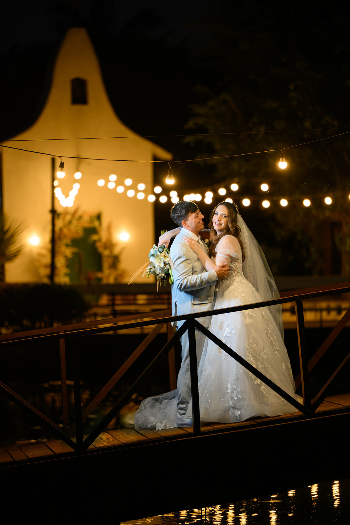 Casal na ponte com a capela iluminada ao fundo