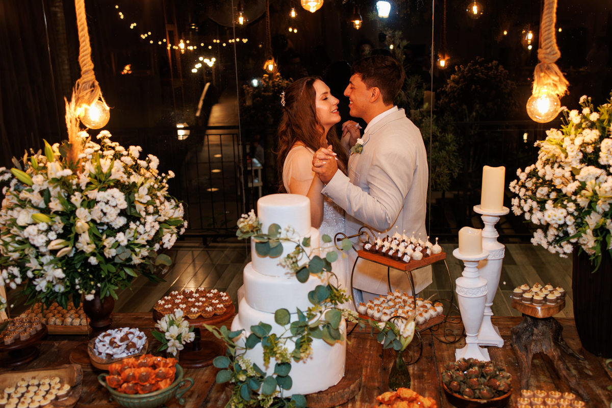 Casal se beijando diante da mesa do bolo