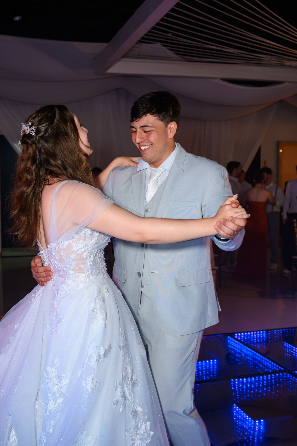 Casal girando durante a primeira dança sobre a pista iluminada
