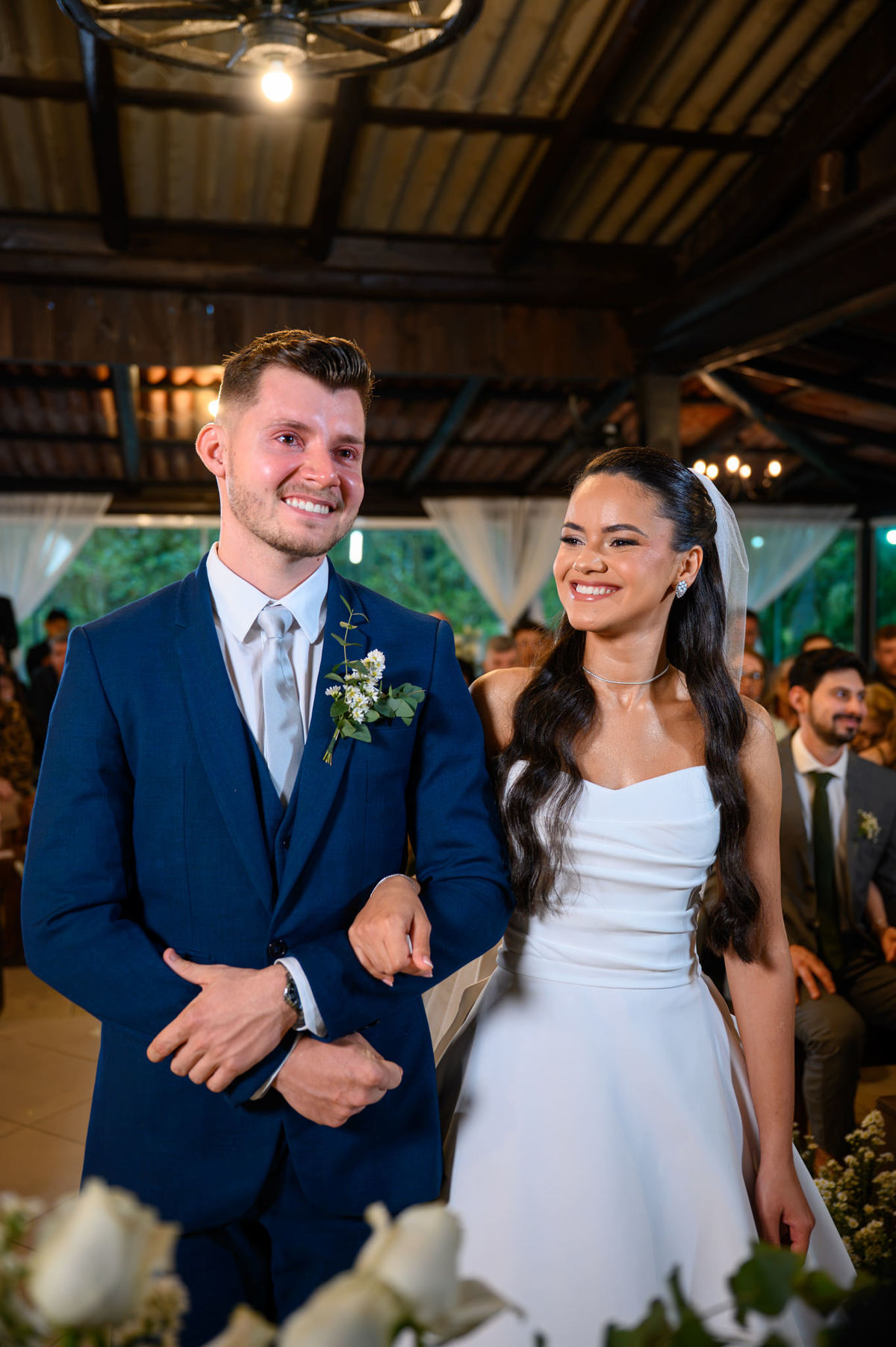 Noivos sorrindo juntos diante dos convidados