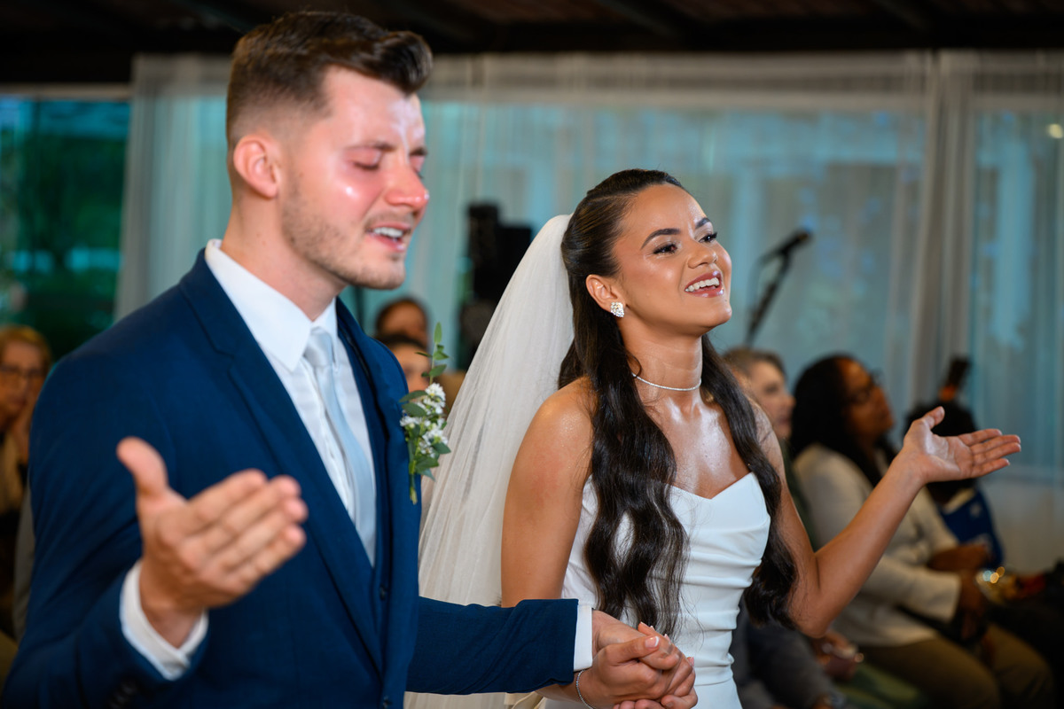 Noivos com as mãos levantadas durante momento de louvor