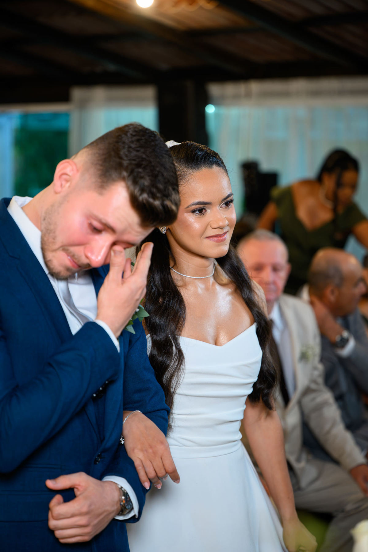 Noivo emocionado enxugando lágrimas ao lado da noiva