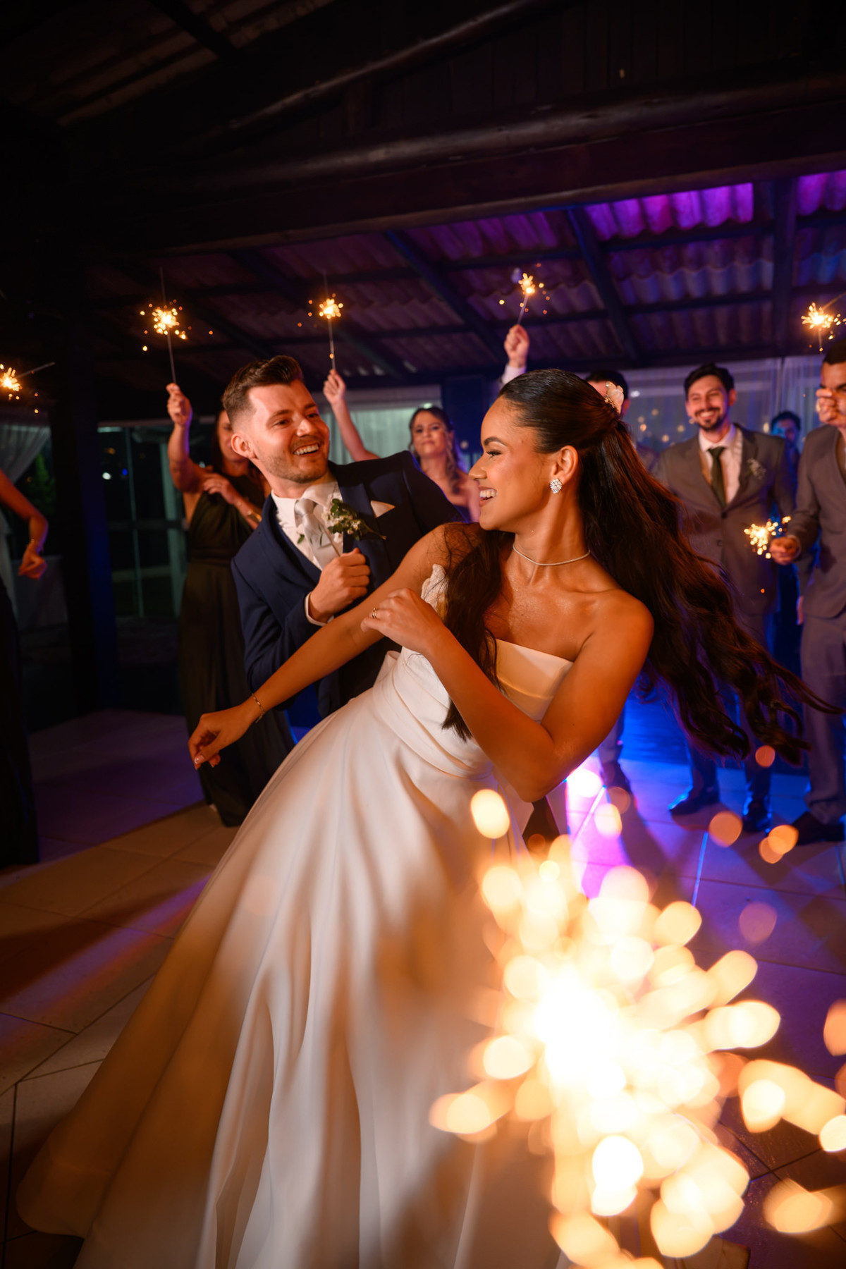 Noivos durante a dança com luzes desfocadas em primeiro plano