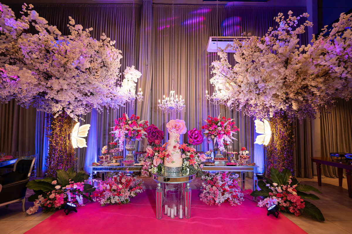 Mesa principal com decoração floral rosa para festa de debutante