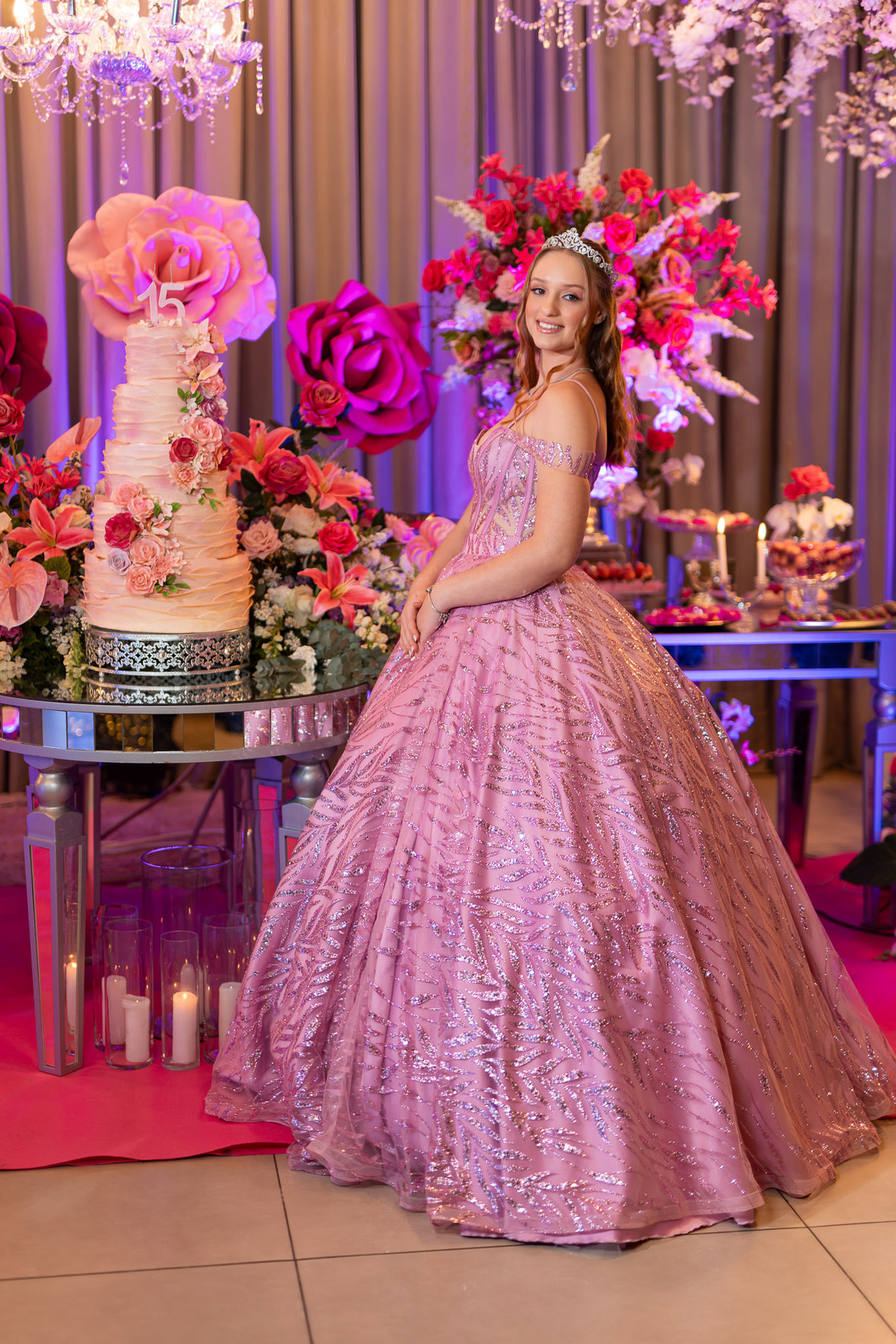 37. Debutante de vestido rosa ao lado do bolo de 15 anos
