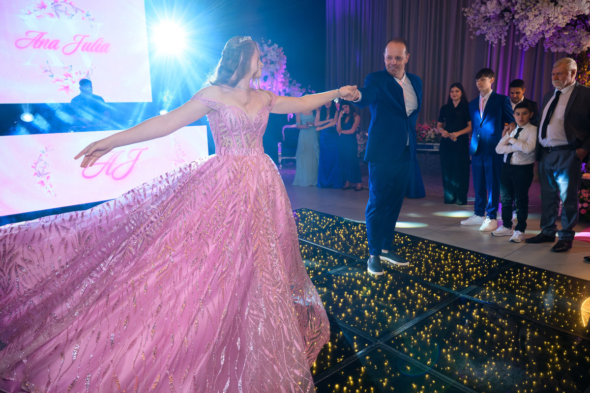 59. Pai girando a debutante durante a valsa na pista iluminada
