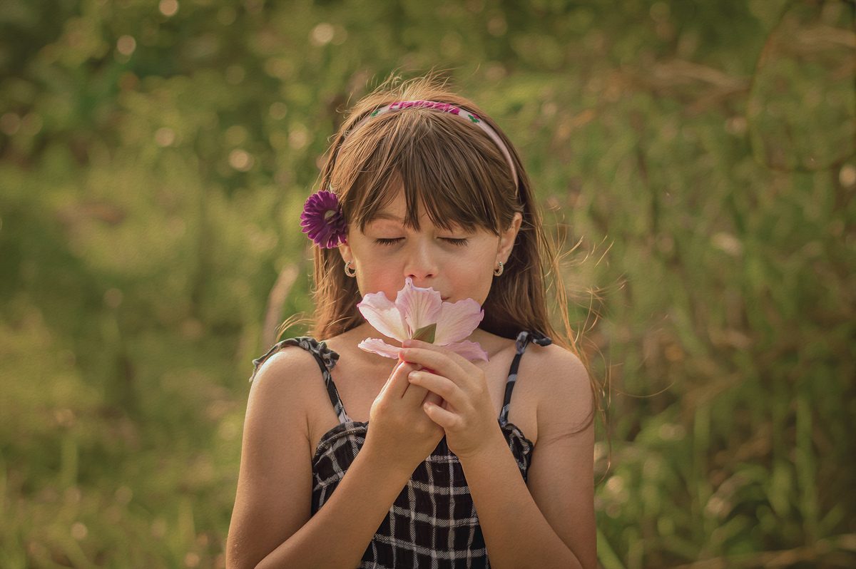 foto menina cheirando uma flor