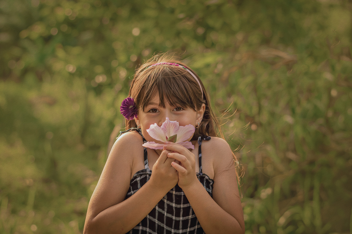 foto de menina segurando uma flor na natureza