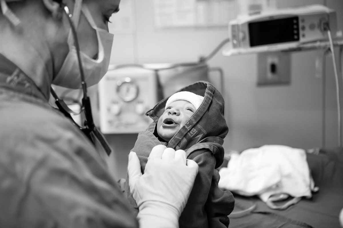 bebê enroladinho no lençol de hospital fazendo biquinho