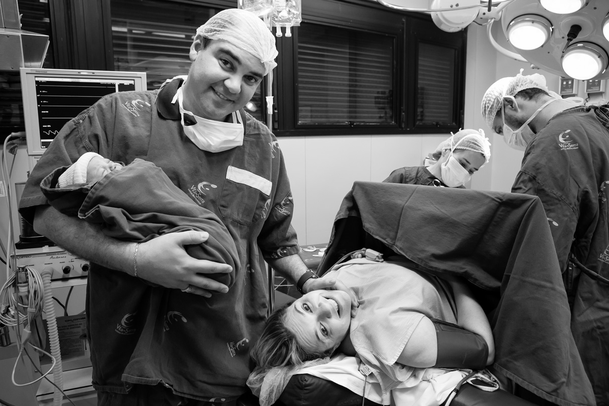 pai em pé segurando o bebê com a mãe