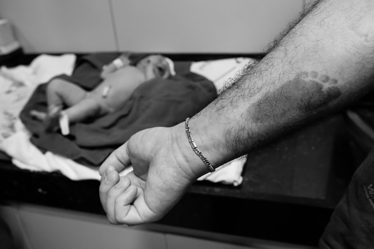 braço do pai com o pézinho do bebê marcado