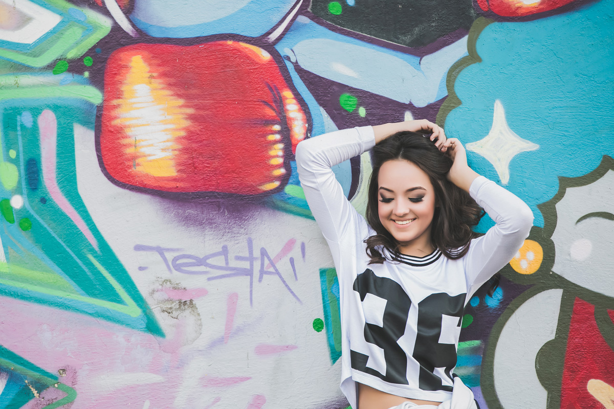 menina sorrindo encostada no muro