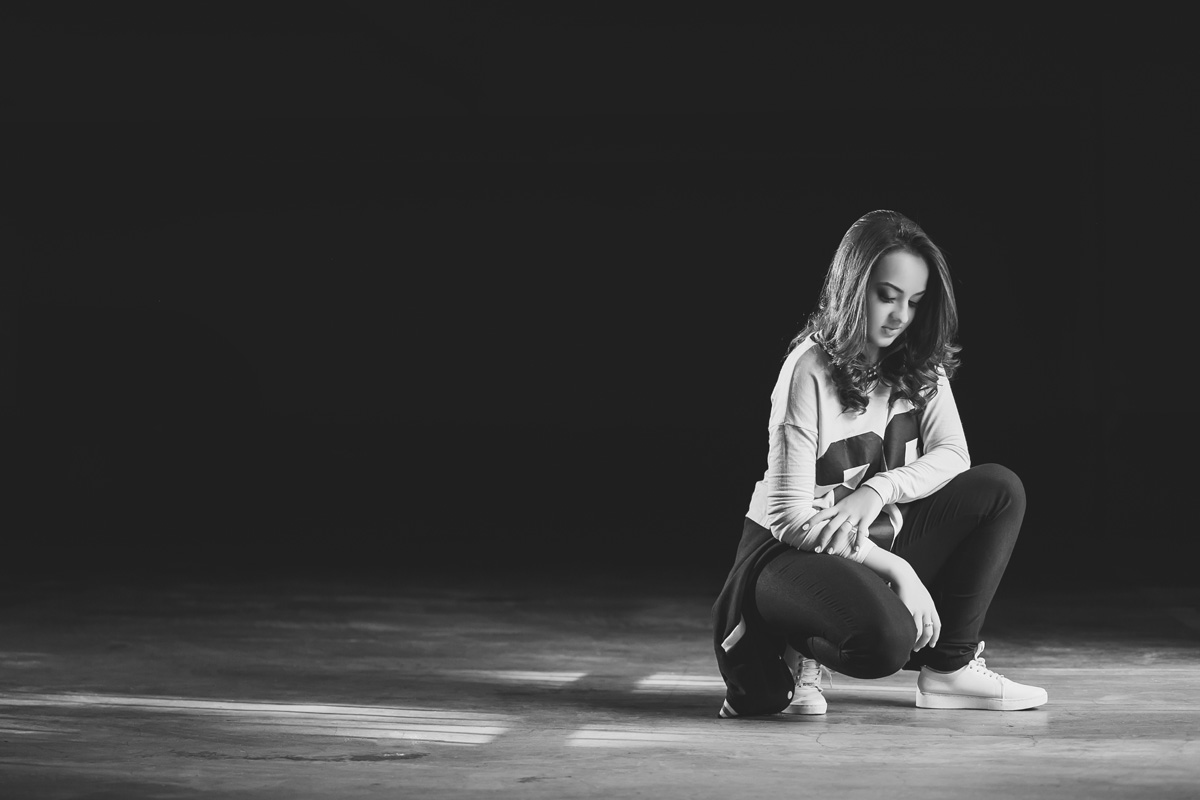 menina ajoelhada em frente ao fundo preto