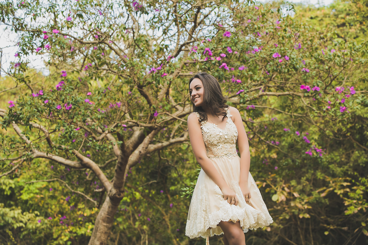 menina em frente a árvores com flores rosas