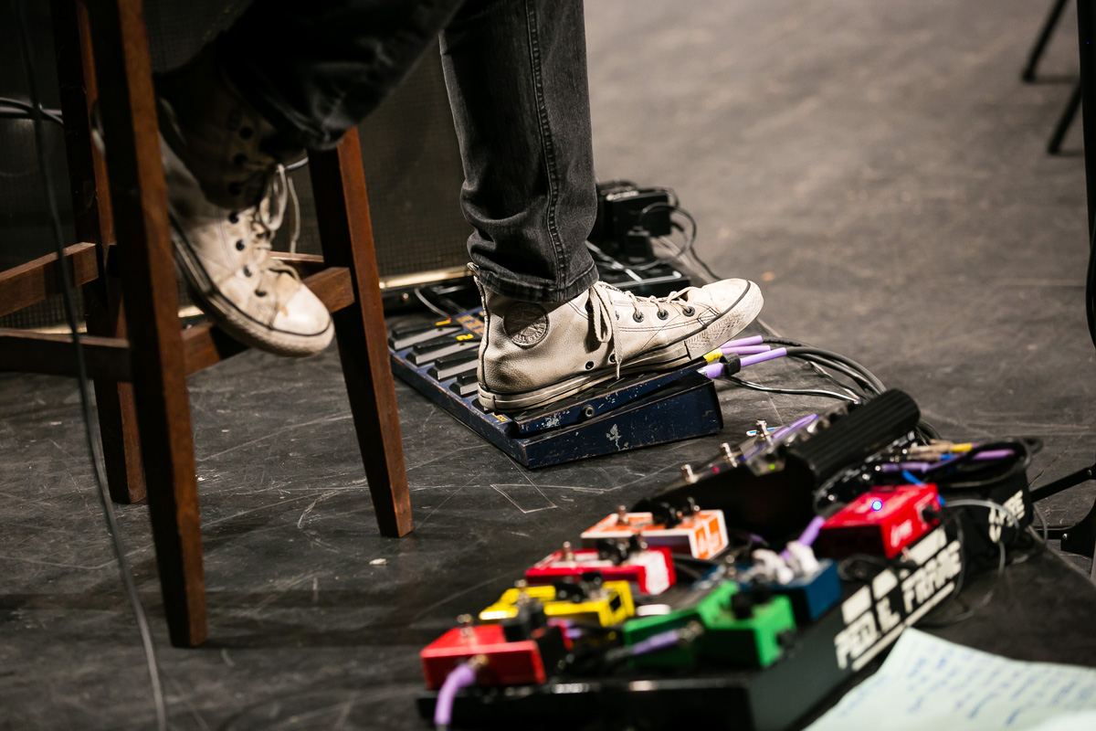 homem com o pé no pedal de guitarra