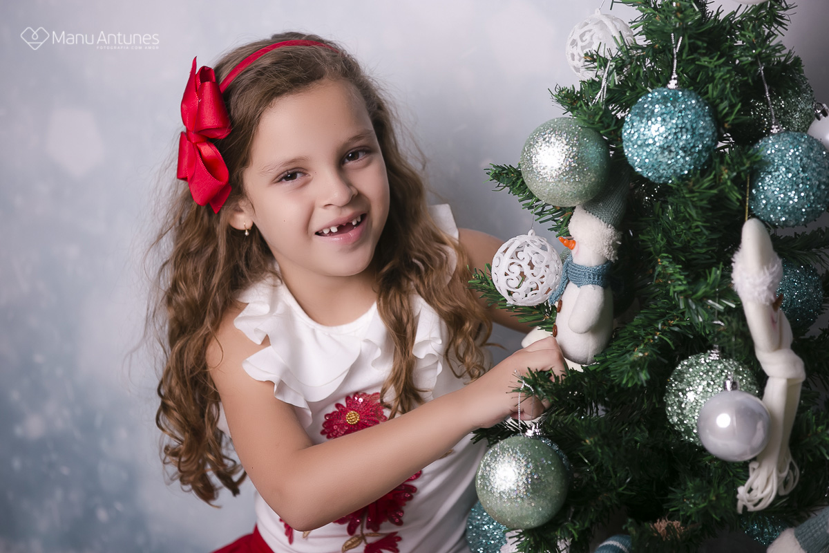 menina mexendo na árvore de natal