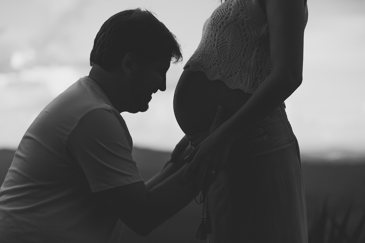silhueta do pai olhando pra barriga da mãe