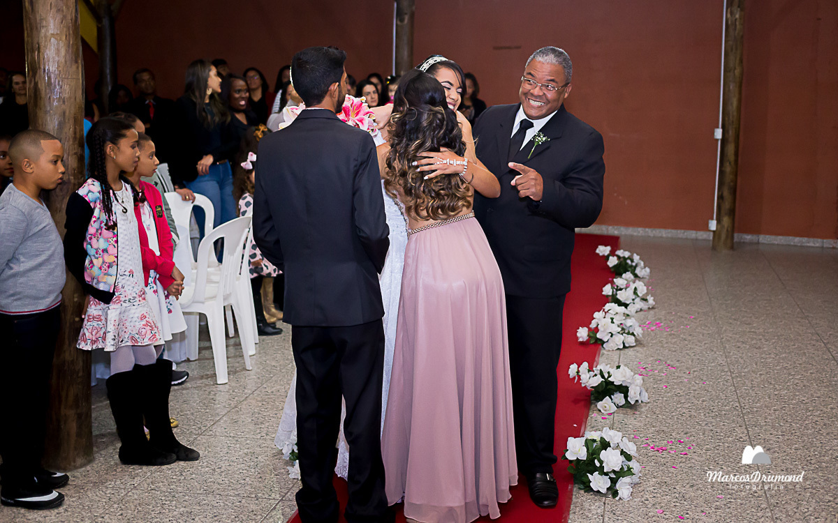 Noivo recebendo a noiva das mãos de seu pai no salão de festa onde foi realizado a cerimônia