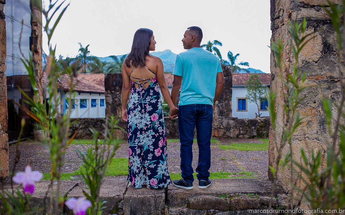 Fotografia de pré casamento onde a noiva está de vestido longo segurando a mão do noivo que está de calça jeans, sapa tênis e camiseta verde