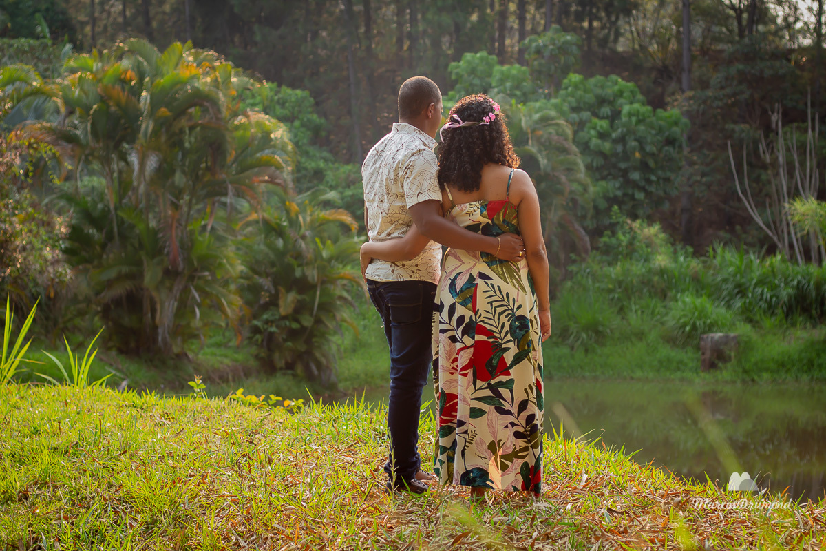 Fotografia de pré casamento onde o casal está de costas olhando para frente onde há uma lagoa e estando muito felizes 