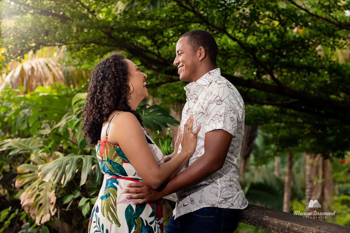 Fotografia de pré casamento onde os noivos estão de frente um para o utro e a noiva está com as mãos no peito do noivo e o noivo com as mãos na cintura da noiva onde ambos estão sorrindo