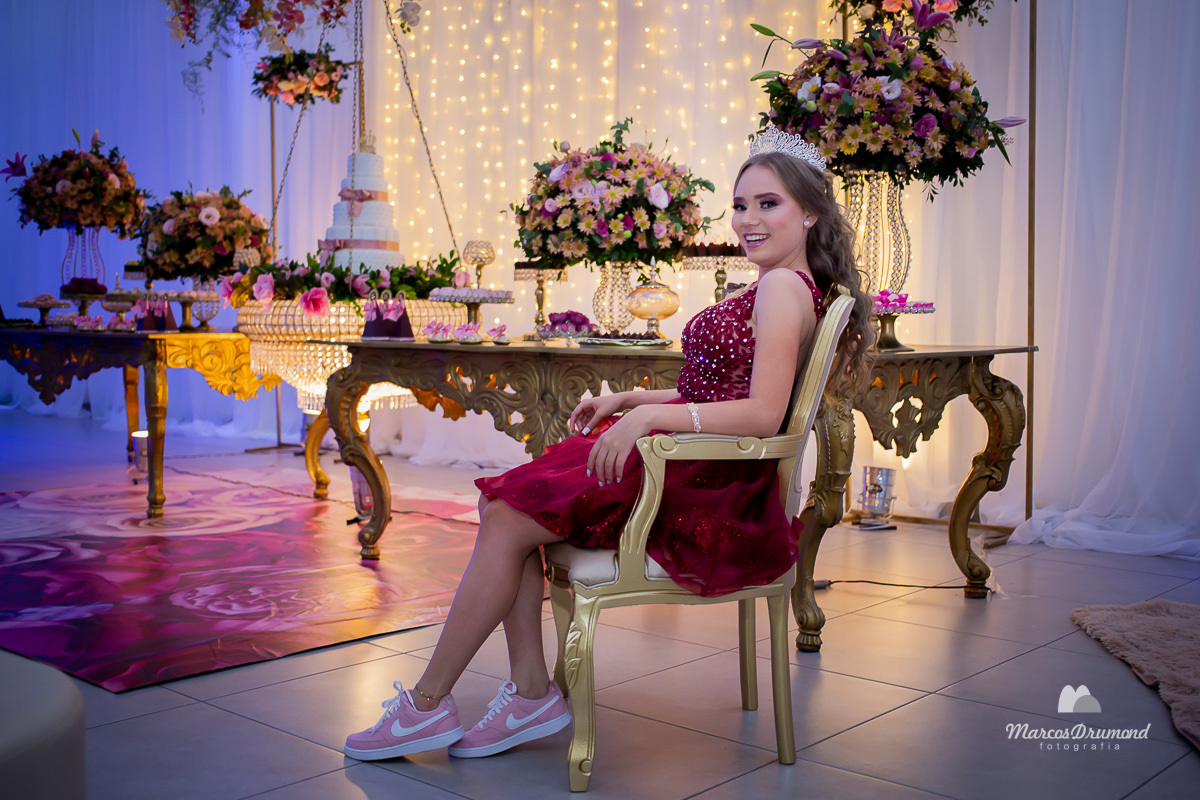 A modelo Lívia Mascarenhas, na comemoração de seus 15 anos está sentada olhando para a câmera para ser fotografada, a debutante está muito feliz, pois não é todo dia que pode comemorar quinze anos e ela está aproveitante a festa de 15 anos para ser foto