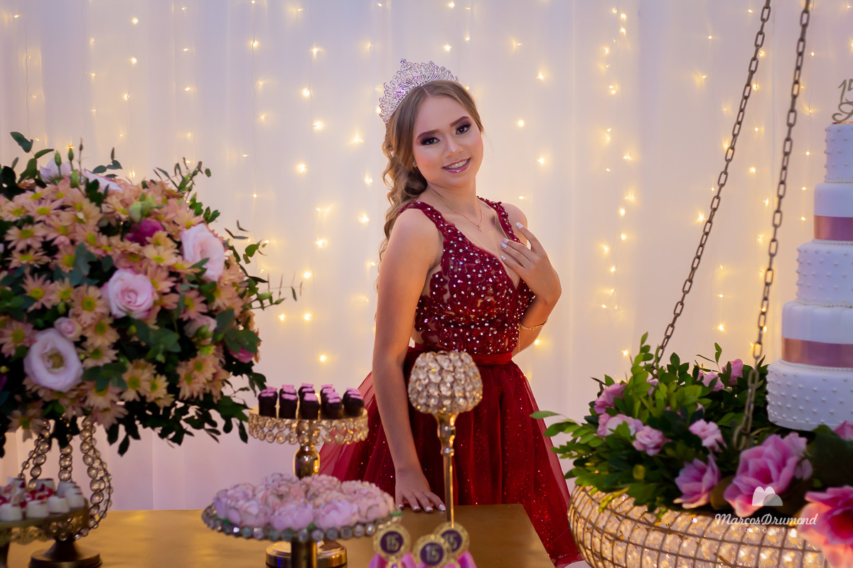 Lívia Mascarenhas em seus 15 anos olhando para a câmera fotográfica para ser fotografada em sue aniversário de 15 anos, pois ao lado da mesa com uma mão encima dela a foto fica melhor. A debutante gosta de ser fotografada sempre olhando para a câmera foto