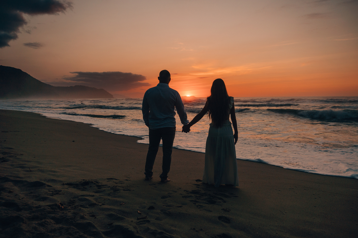 Casal contemplando o mar durante ensaio fotográfico na praia de Ubatuba.