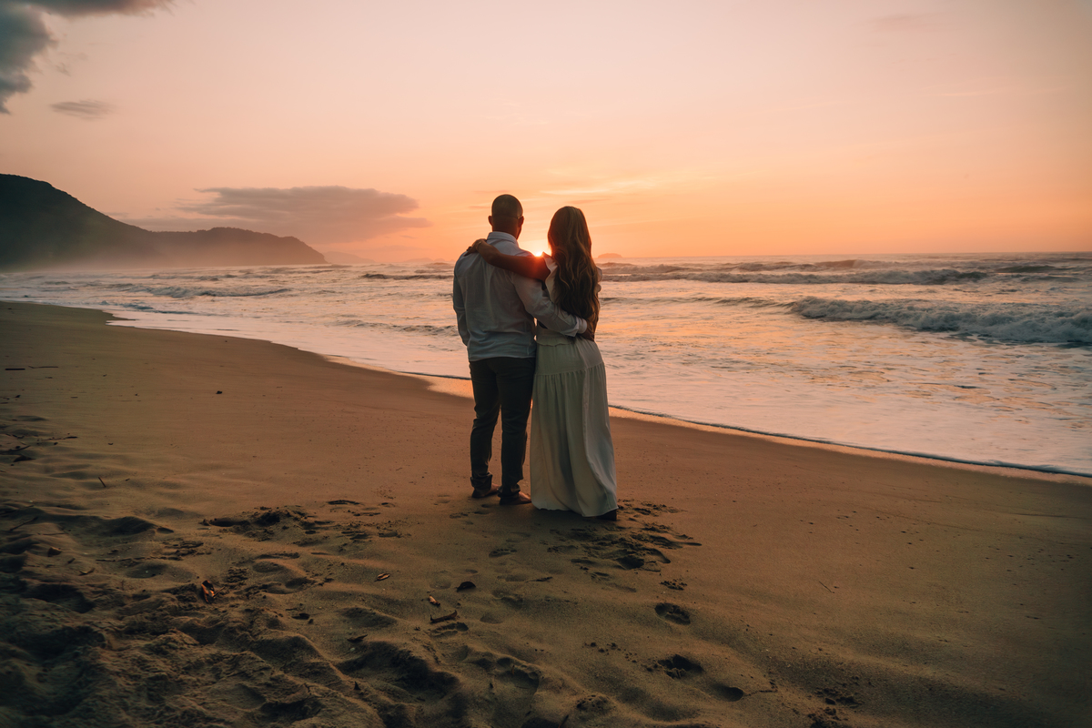 Casal contemplando o mar durante ensaio fotográfico na praia de Ubatuba.