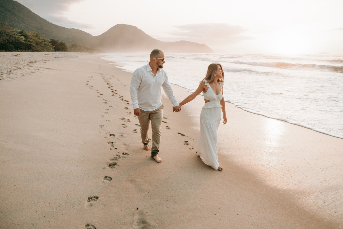 Casal caminhando na areia durante ensaio fotográfico na Praia de Itamambuca em Ubatuba.