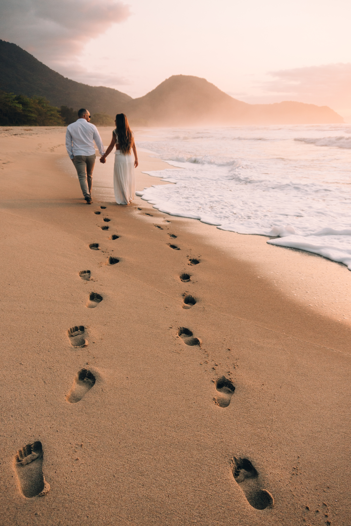 Casal caminhando na areia durante ensaio fotográfico na Praia de Itamambuca em Ubatuba.