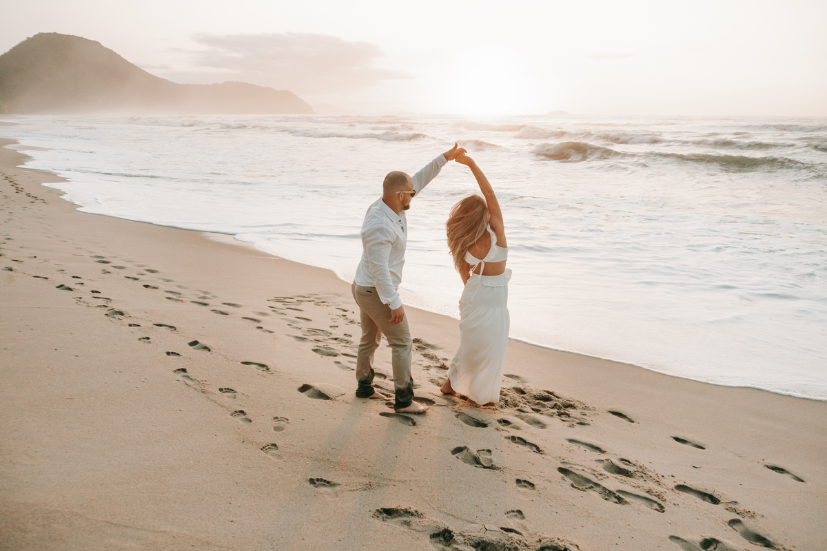 Casal fotografado na Praia de Itamambuca em Ubatuba durante ensaio pré-casamento ao pôr do sol com luz natural.