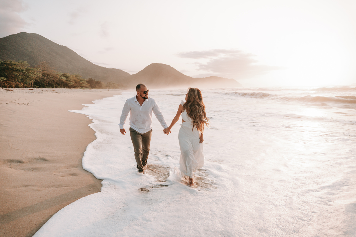 Casal caminhando na areia durante ensaio fotográfico na Praia de Itamambuca em Ubatuba.