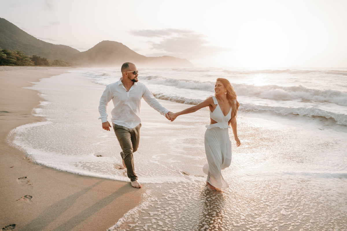 Casal caminhando na areia durante ensaio fotográfico na Praia de Itamambuca em Ubatuba.