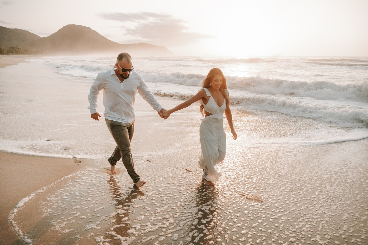 Casal caminhando na areia durante ensaio fotográfico na Praia de Itamambuca em Ubatuba.