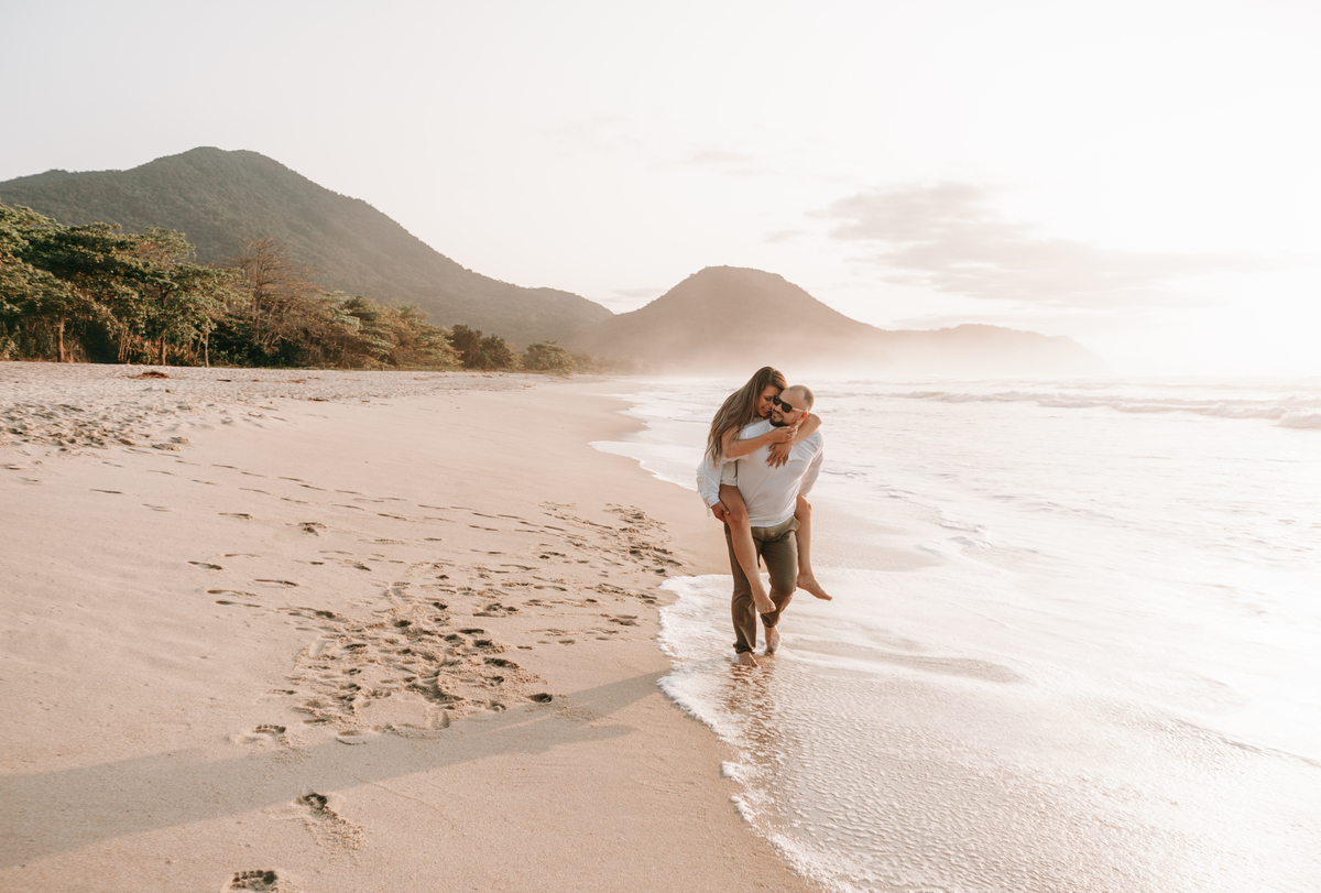 Casal caminhando na areia durante ensaio fotográfico na Praia de Itamambuca em Ubatuba.