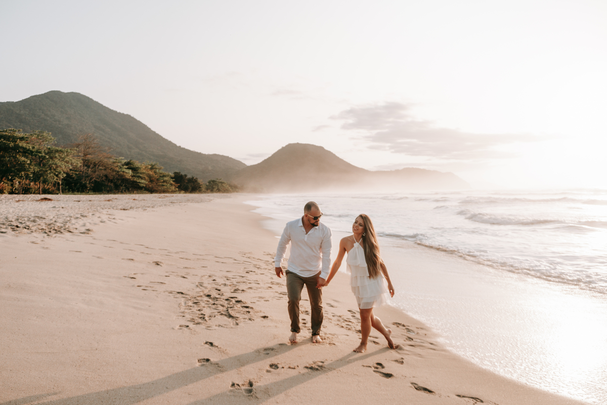 Casal caminhando na areia durante ensaio fotográfico na Praia de Itamambuca em Ubatuba.