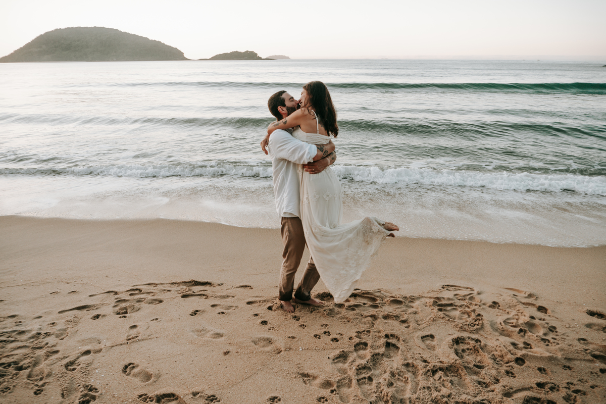 Casal participando de ensaio romântico na praia com luz natural.