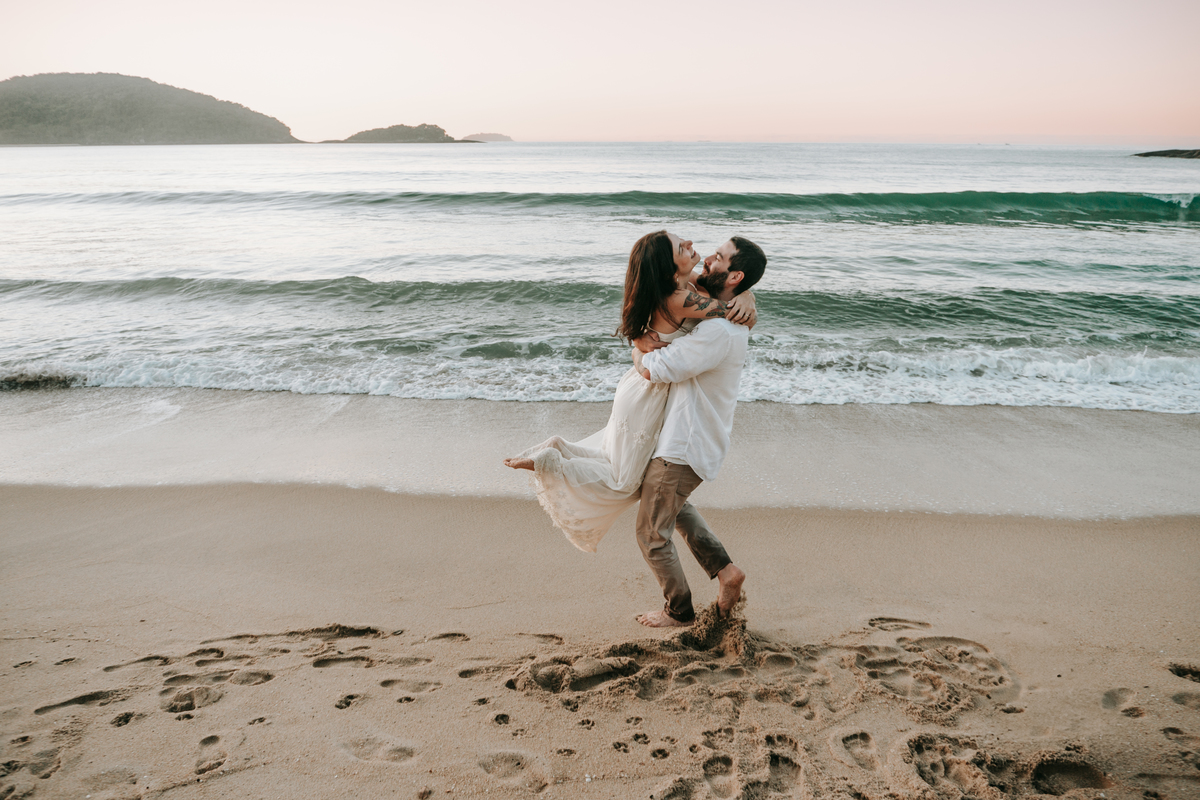 Casal participando de ensaio romântico na praia com luz natural.