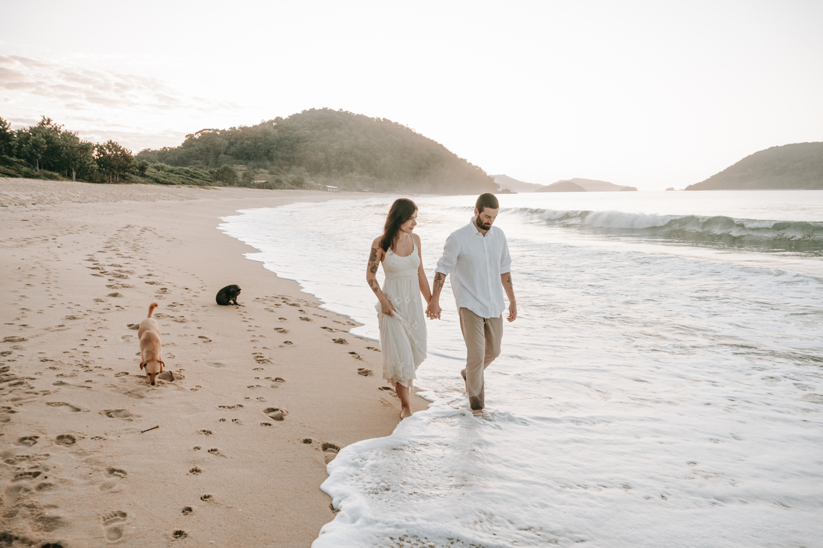 Casal caminhando na beira do mar durante ensaio fotográfico em Ubatuba.