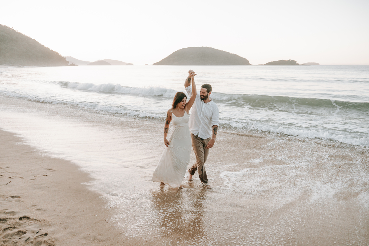 Casal caminhando na beira do mar durante ensaio fotográfico em Ubatuba.