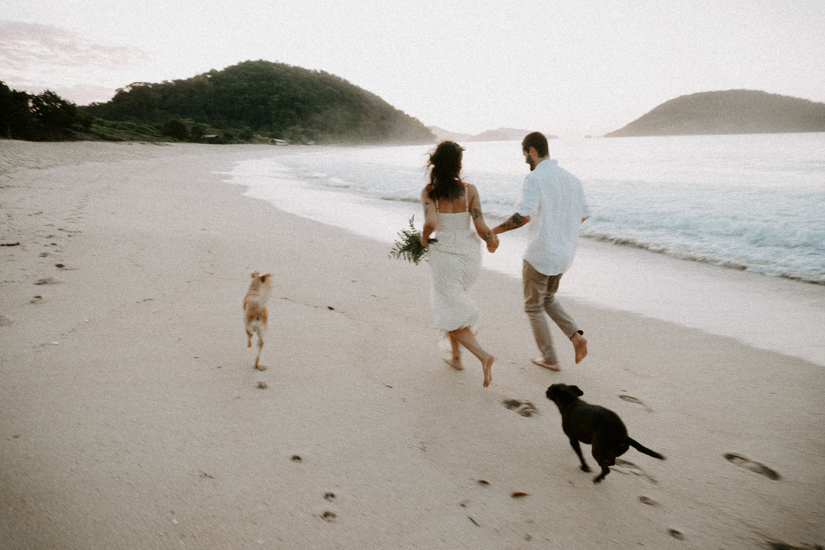 Casal brincando com seu cachorro durante ensaio pré-wedding ao ar livrelivre.