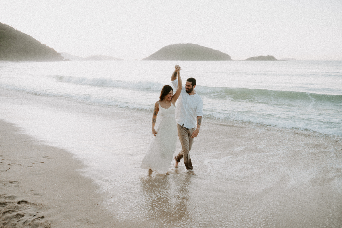 Casal caminhando na beira do mar durante ensaio fotográfico em Ubatuba.
