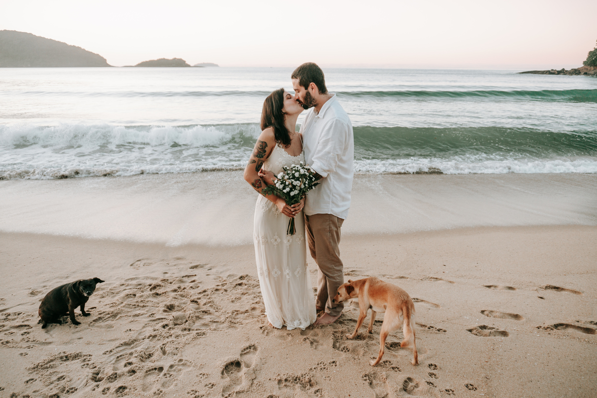 Casal brincando com seu cachorro durante ensaio casal ao ar livre
