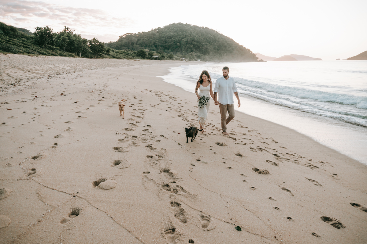 Casal caminhando na beira do mar durante ensaio fotográfico em Ubatuba.