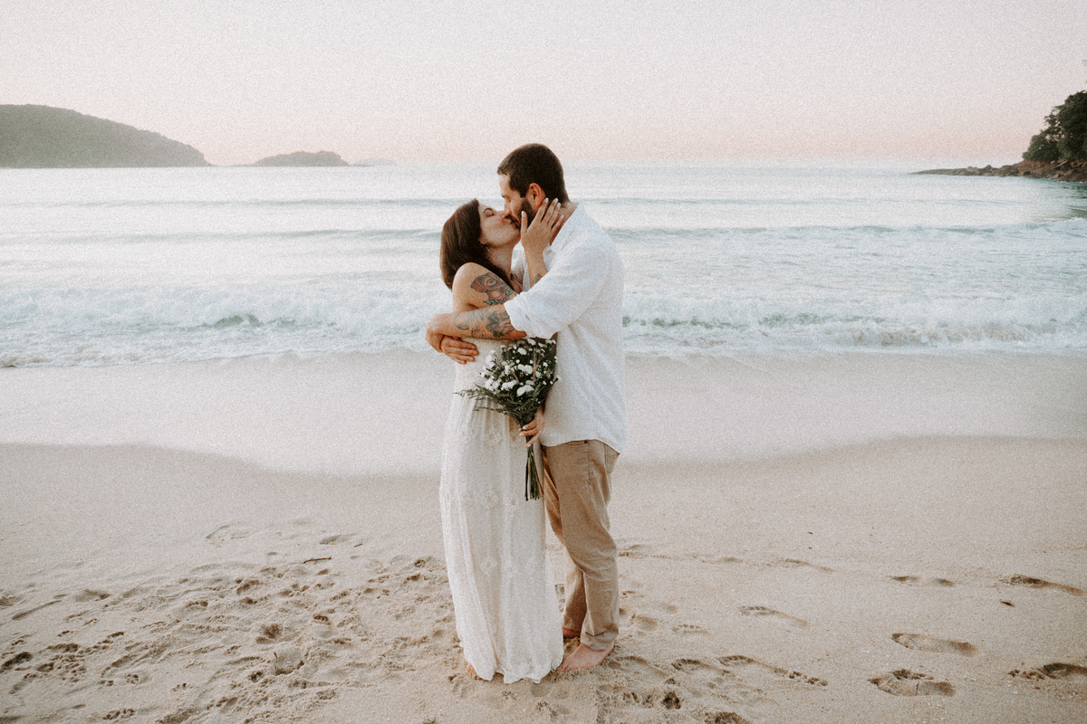 Casal participando de ensaio romântico na praia com luz natural.